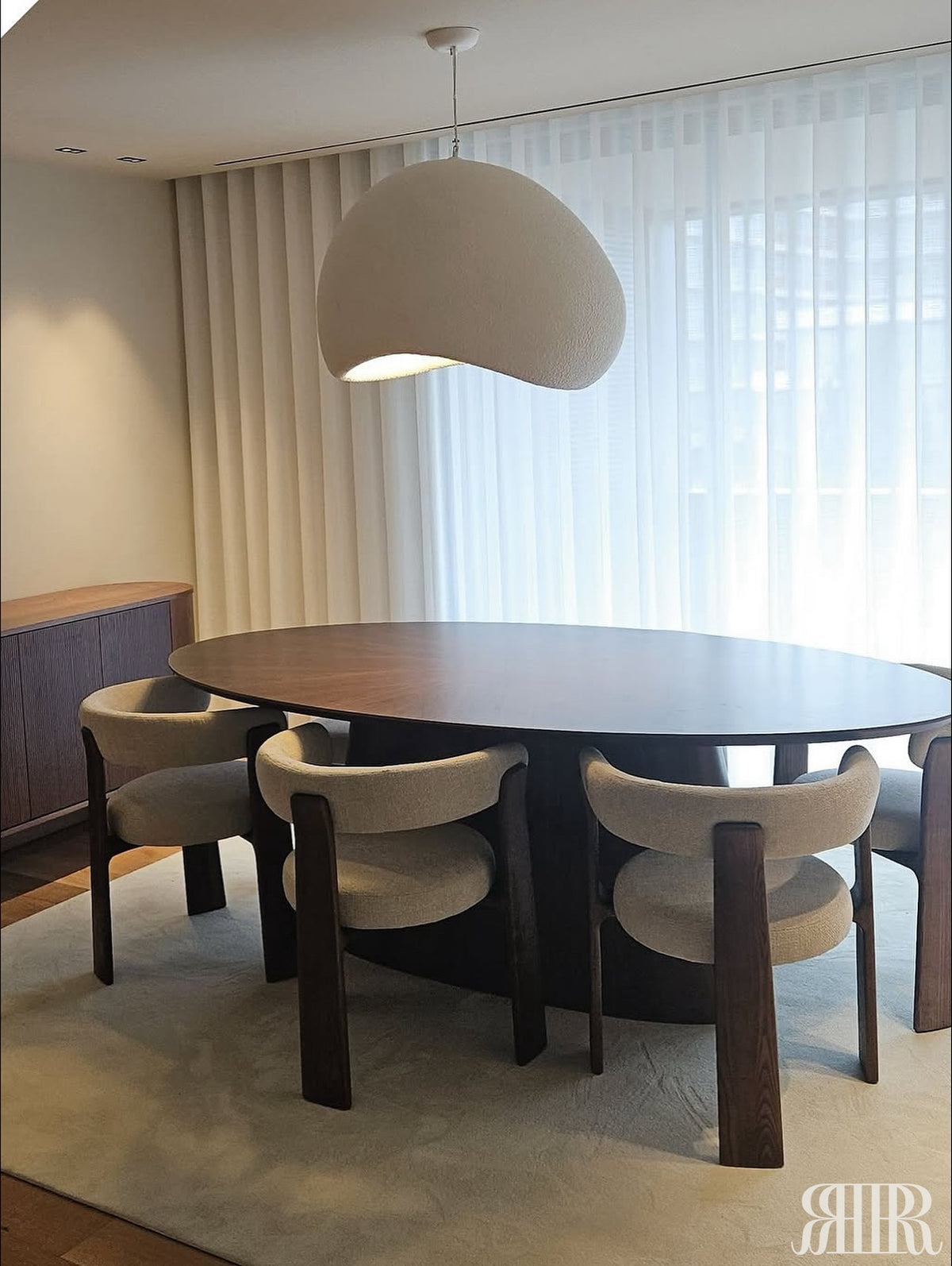 Dining area with a round wooden table and four chairs in a modern interior setting.