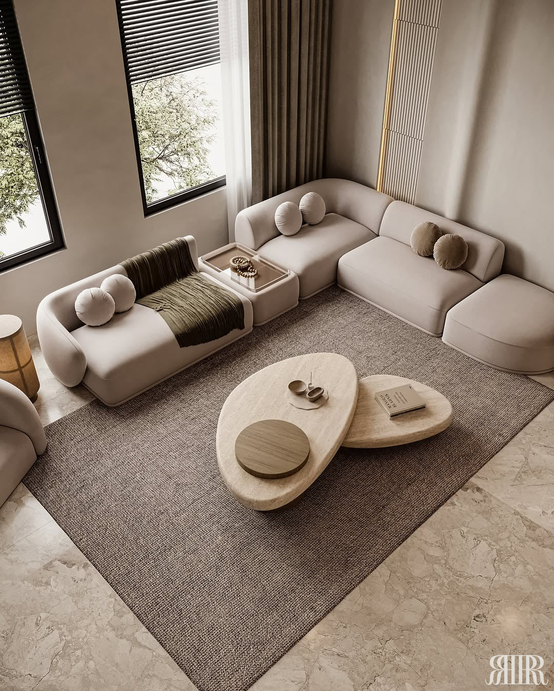A modern living room featuring a curved modular sofa in light beige, a matching low coffee table with organic-shaped wooden tops, and a large textured brown area rug on a stone floor.