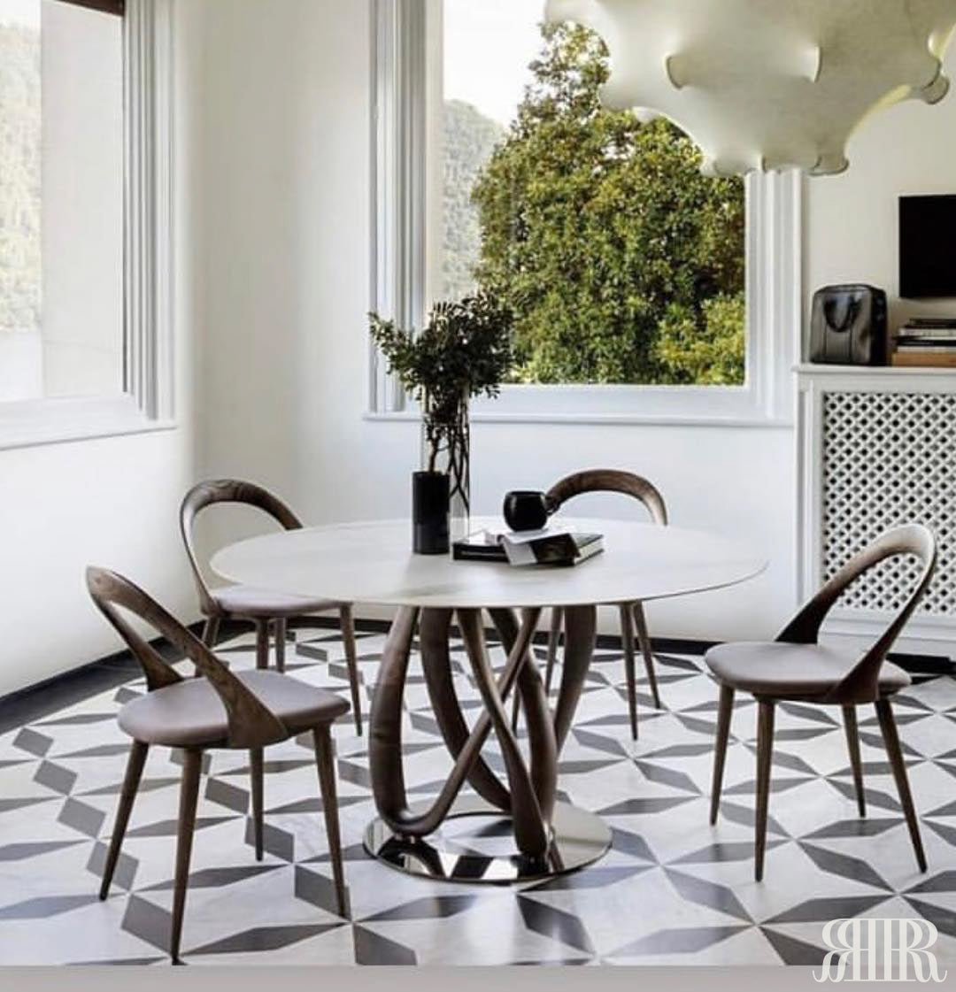 Modern dining room with a round table and chairs on a patterned floor.