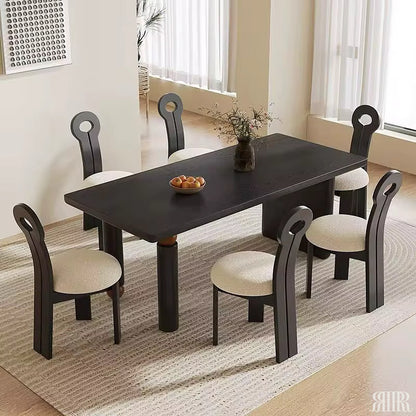 Dining table set with chairs in a room with large windows.