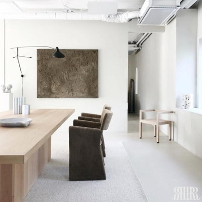 Modern dining area with a long wooden table and chairs in a minimalistic setting.
