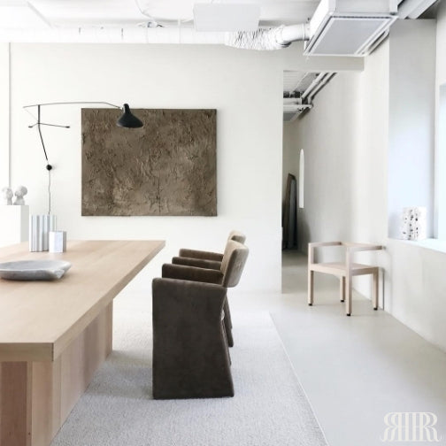 Modern dining area with a long wooden table and chairs in a minimalistic setting.