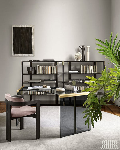 Modern office setup with a black L-shaped desk, bookshelves, and a plant.