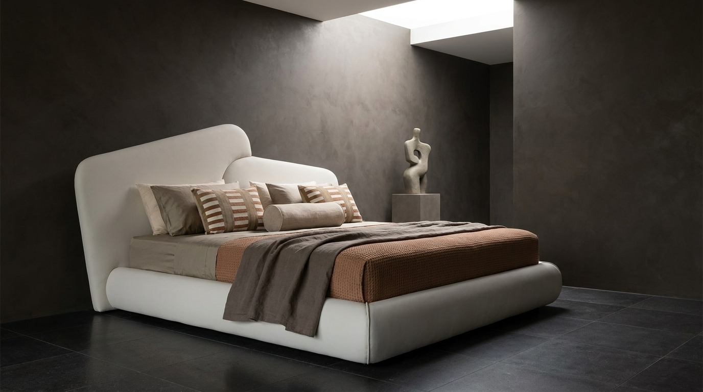 A modern low-profile platform bed with a curved white headboard and footboard, styled with neutral beige and brown bedding, set against a dark textured wall in a minimalist bedroom.