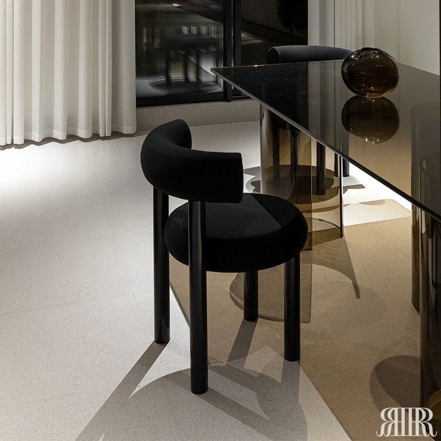 Modern black chair and table set in a minimalistic room with white walls and light gray floor.