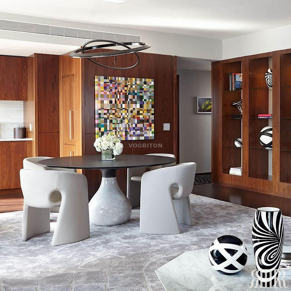 Modern dining room with a round table and chairs, decorative vases, and abstract art on the wall.