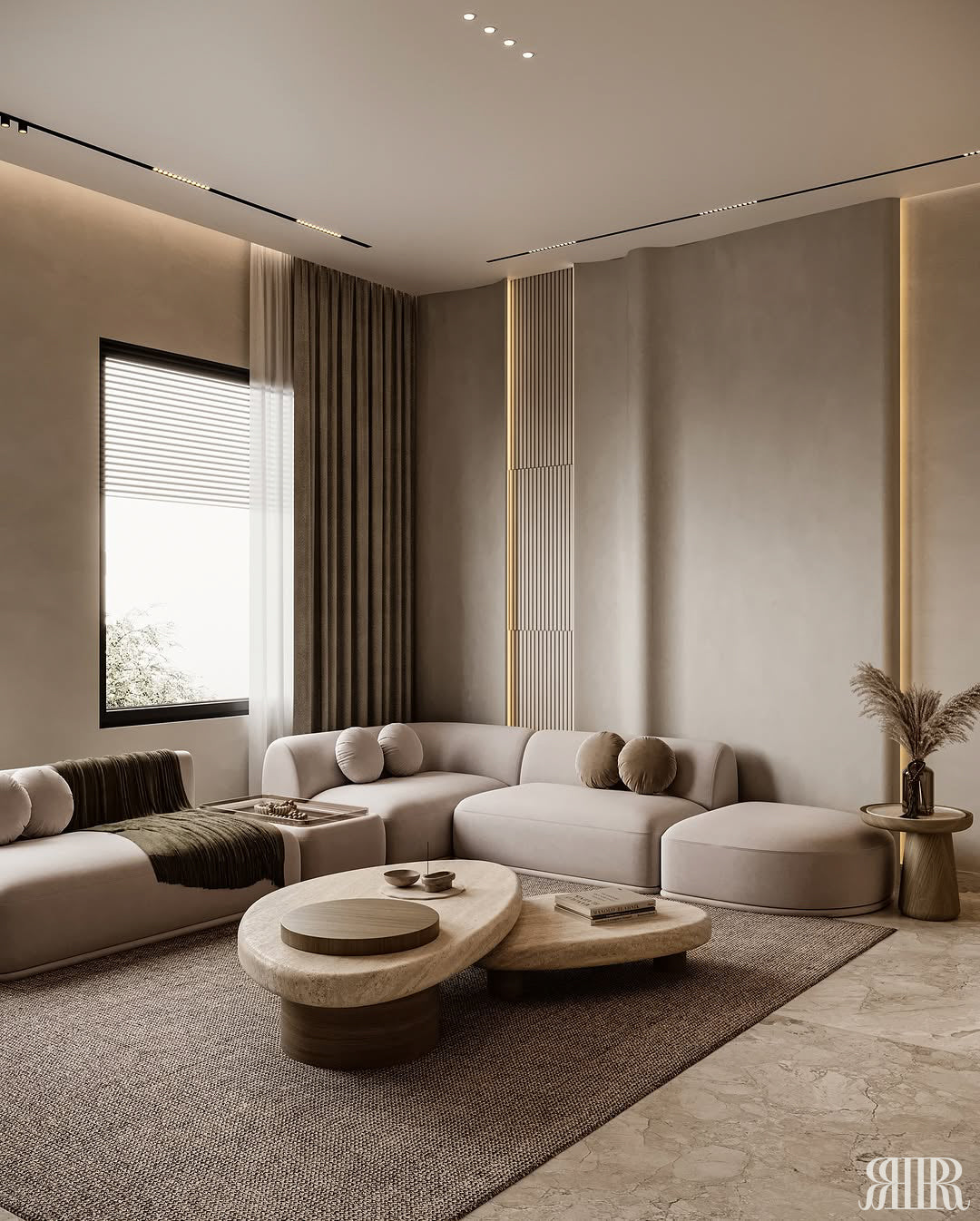A modern living room featuring a light beige sectional sofa, two organic-shaped low coffee tables, a large textured brown area rug, and warm ambient lighting.