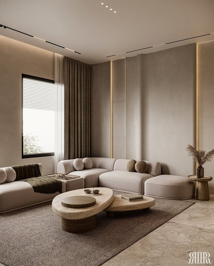 A modern living room featuring a light beige sectional sofa, two organic-shaped low coffee tables, a large textured brown area rug, and warm ambient lighting.