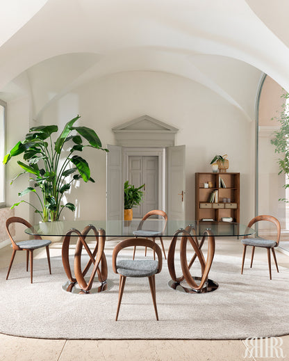 Modern dining room with a glass table and wooden chairs in a bright, minimalistic setting.