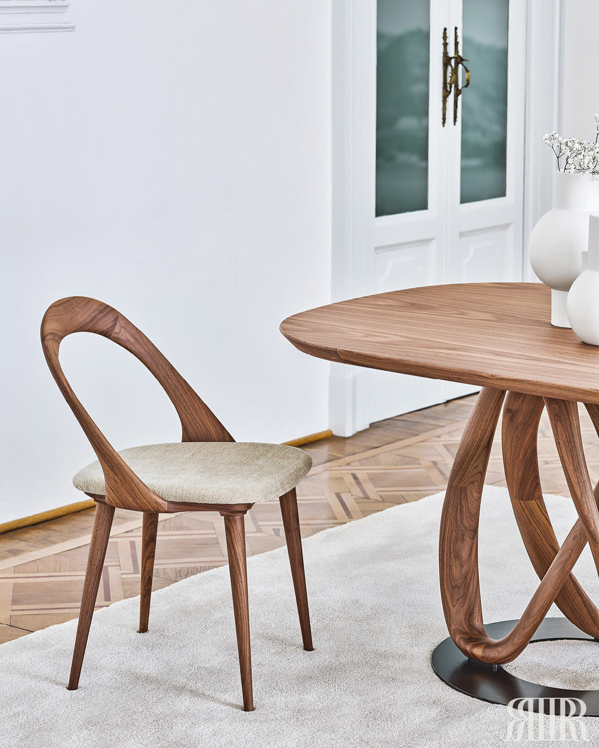 Wooden dining table and chair in a room with white walls and a rug.