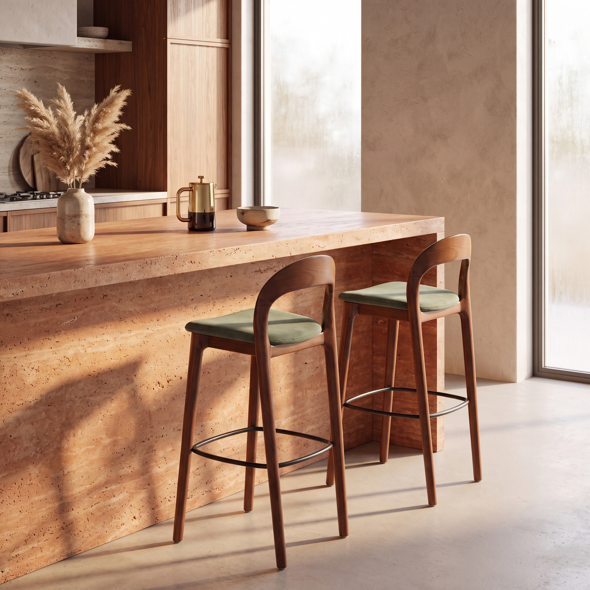 Two wooden bar stools with green upholstered seats are placed at a stone-topped kitchen island in a warm, modern interior with large windows and natural light.